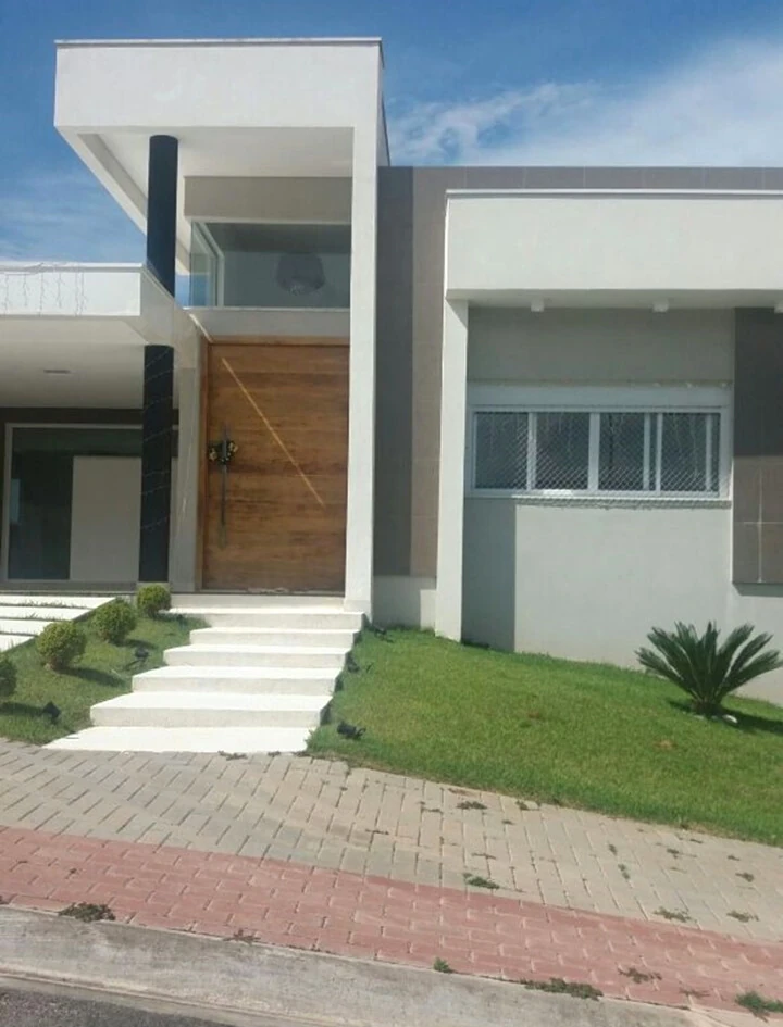 Fachada clara com porta de madeira, degraus e jardim na entrada.