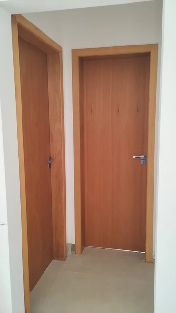 Duas portas internas de madeira em um corredor de paredes claras.