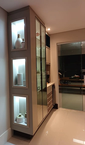 Cristaleira com portas de vidro e nichos iluminados na lateral.